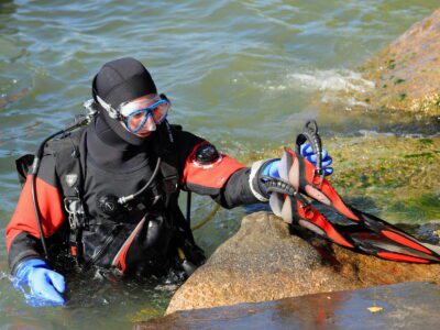 Der PADI Dry Suit Diver-Schüler bereitet sich auf seinen ersten Tauchgang im Trockentauchanzug vor.